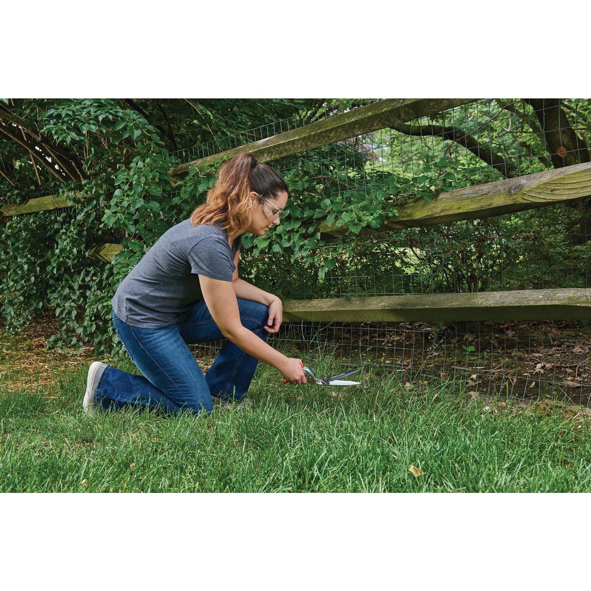 Swivel grass shears being used by a person to trim grass outdoors.