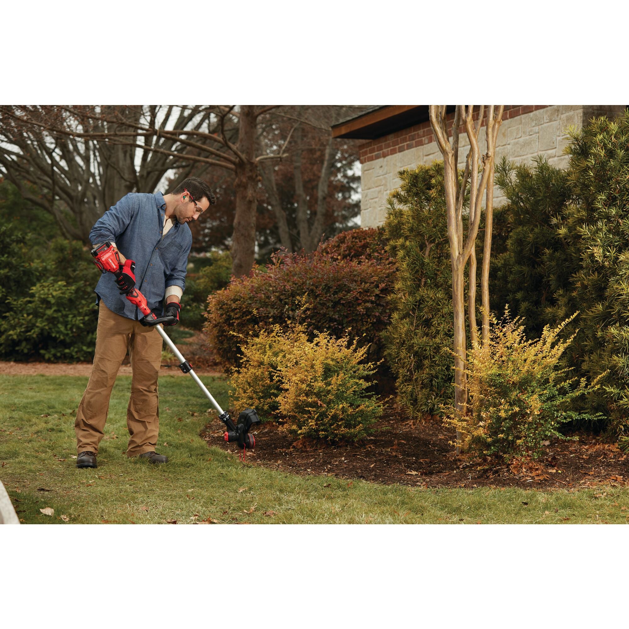 20 volt cordless 13 inch weedwacker string trimmer edger with push button feed being used by a person to trim grass outdoors.