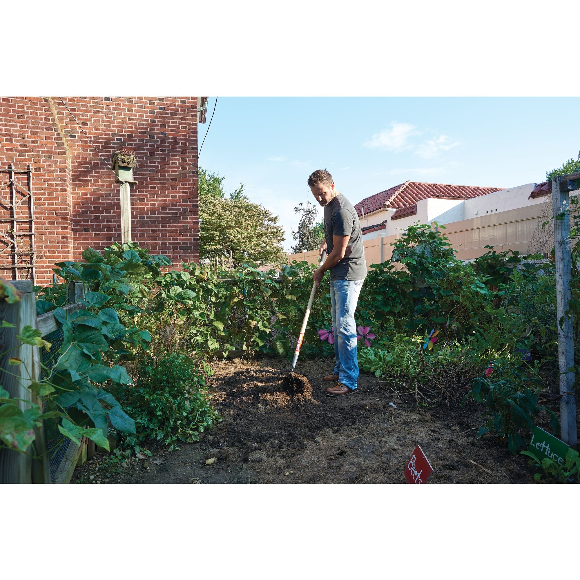 Wood handle garden hoe being used by a person.