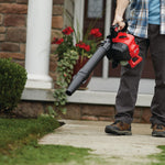 27 C C 2 cycle full crank engine gas leaf blower being carried by a person outdoors.