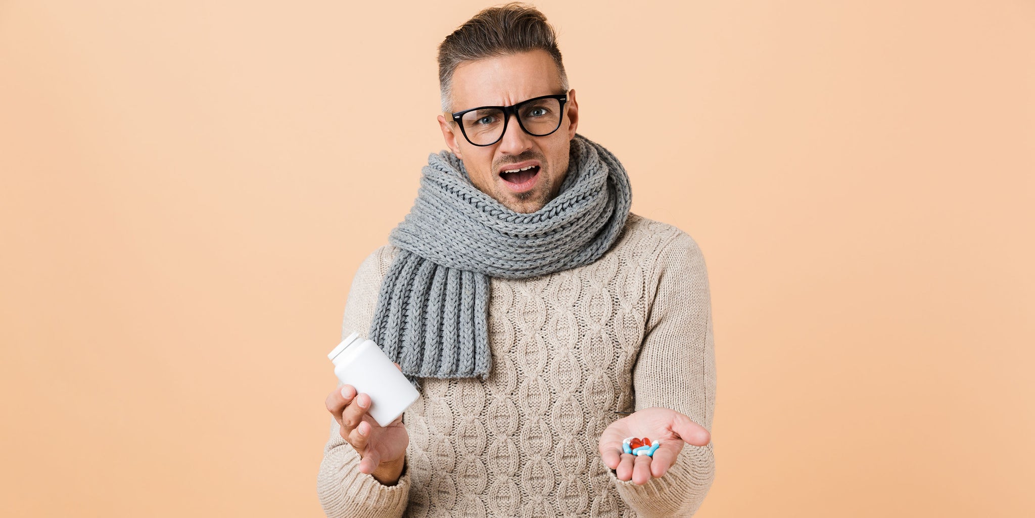 Man making a confused face holding a handful of vitamins.