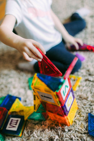 Young child's hands building with colorful blocks