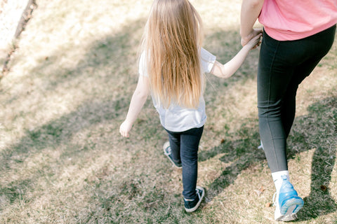 Young girl holding hands with an adult while walking outside