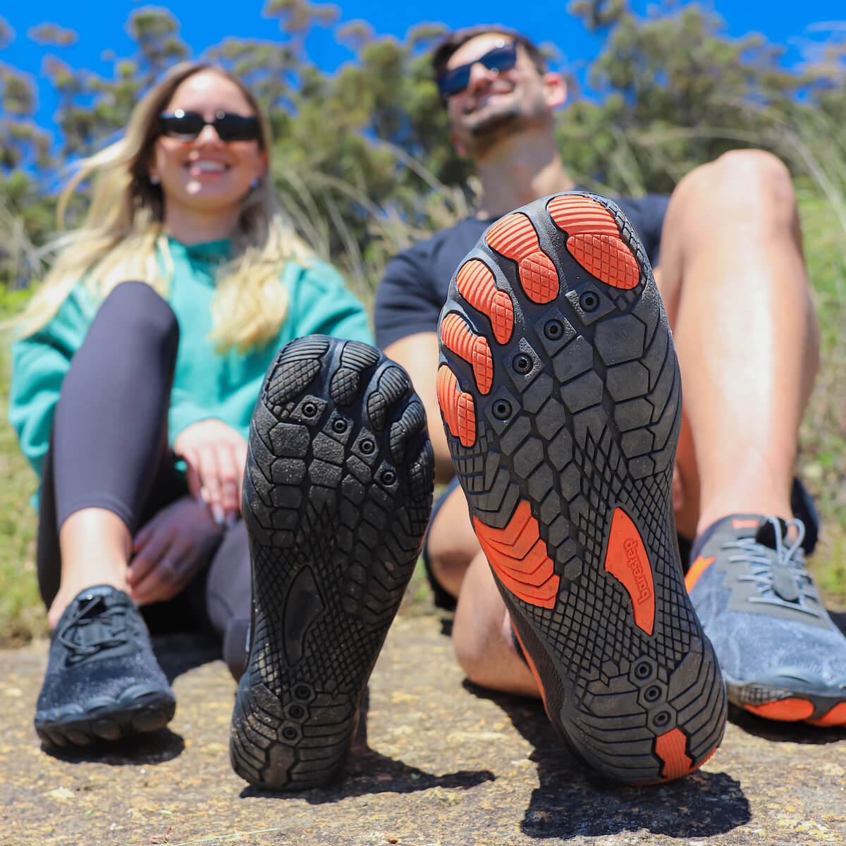 A man and woman sitting next to eachother, smiling, both wearing Barestep Active 2.0 barefoot shoes.