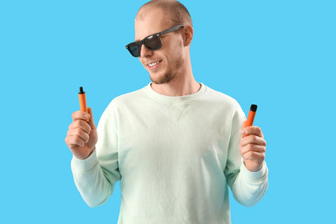 A guy holding two elf bar vapes in his hand