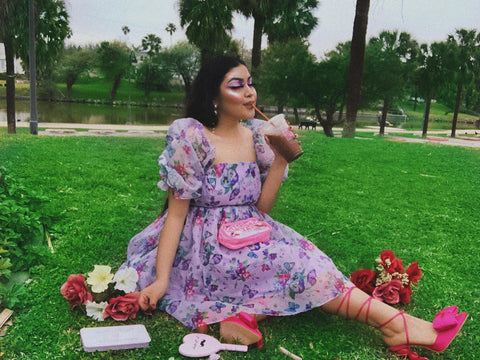 Young Woman in a park sips coffee surrounded by flowers.