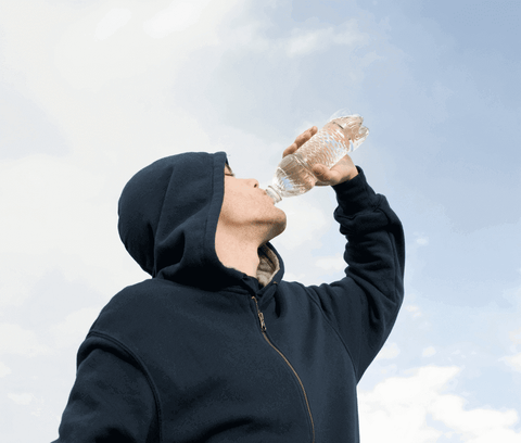 A guy in a hoodie hydrating himself with a bottle of water