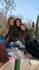 Three friends sharing tapas on the grass and hugging in Madrid.