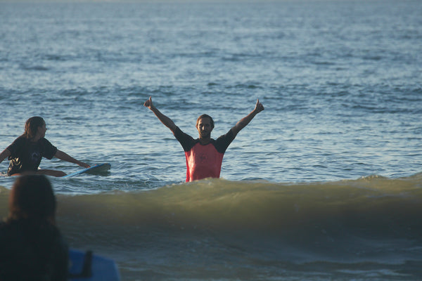 Surf camp instructor giving a thumbs up from the ocean.
