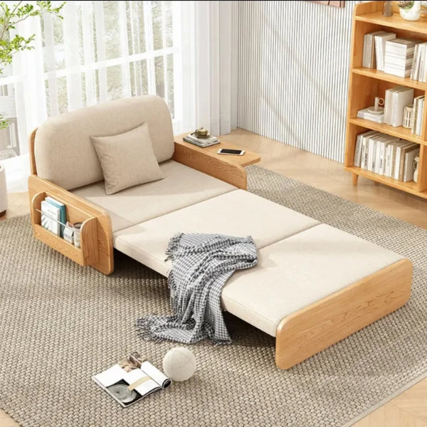 A minimalist, Japanese-inspired convertible sofa bed with a light wood frame and beige cushions, extended to form a sleeping area, complete with built-in side storage pockets.
