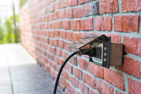 A cord plugged into an outdoor GFCI 110 volt electrical outlet.