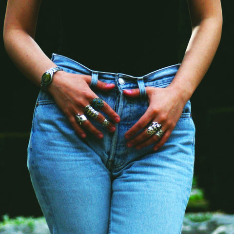 woman wearing black shirt and jeans with hands on her jeans wearing multiple rings