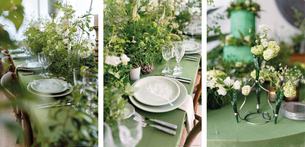 zoom in of a dining table setting with green table cloth and a lot of flowers and leaves decorating it