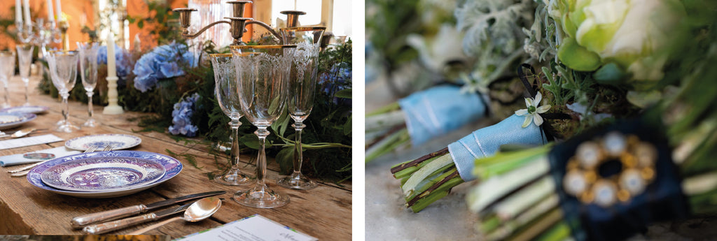 wooden table set up for dining with blue plates and goblets and flowers decoratons