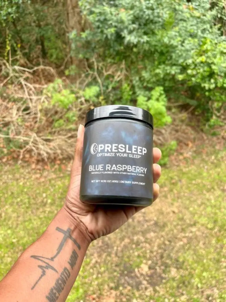 A hand holding a jar of Presleep Blue Raspberry dietary supplement outdoors.