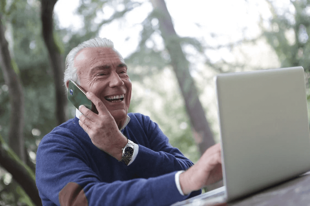 Senior man talking on phone while working on computer