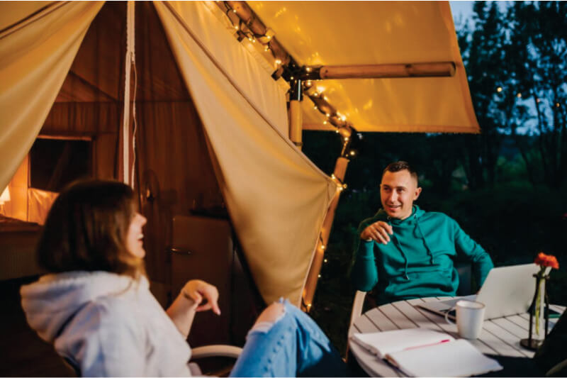 casal sentado no terraço do acampamento marrom em Masai Mara e se divertindo no confortável acampamento de safári Masai Mara