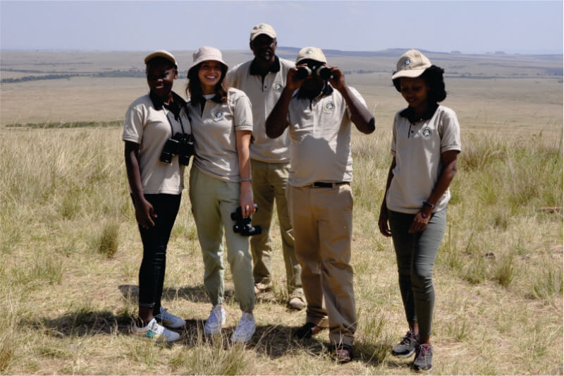 grupo de guías de viaje de Bon Voyage Budget Safari en Kenia tour operador sosteniendo binoculares y tomando fotografías en las llanuras de Masai Mara