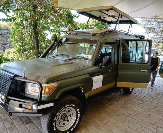 woman boarding custom-built 4x4 green jeep with pop-up-top in Amboseli on well-planned Amboseli safari jeep tours