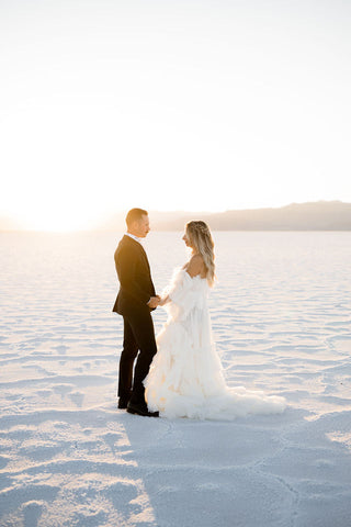 Utah elopement photographer captures couple holding hands while walking on Salt Flats after renting a dress in Utah from Salt Gowns