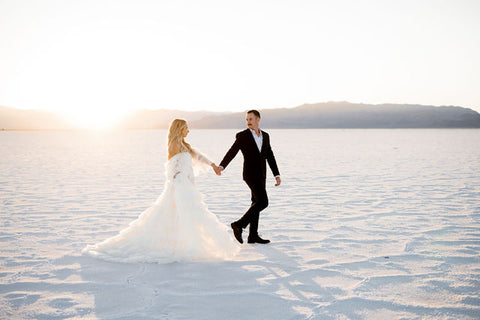 Utah elopement photographer captures couple holding hands while walking on Salt Flats after renting a dress in Utah from Salt Gowns