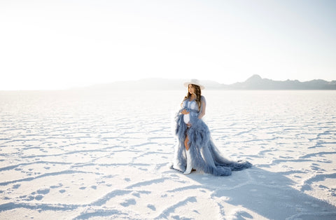 woman wearing blue ruffled dress during maternity session in salt flats