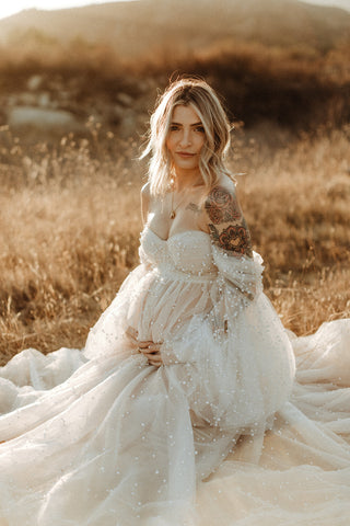 maternity photoshoot in a field in an ivory sheer dress covered in pearls