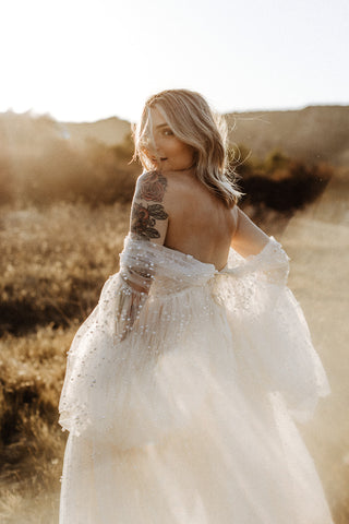 maternity photoshoot in a field in an ivory sheer dress covered in pearls