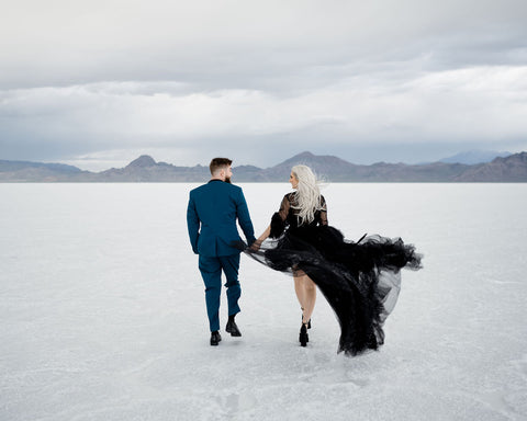 couple in stormy weather at the salt flats, in a suit and flowing black dress