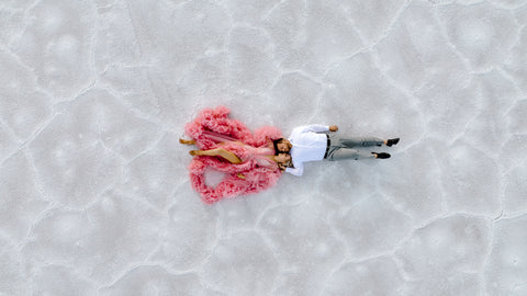 Utah elopement photographer captures man and woman laying down on Salt Flats during engagement session 