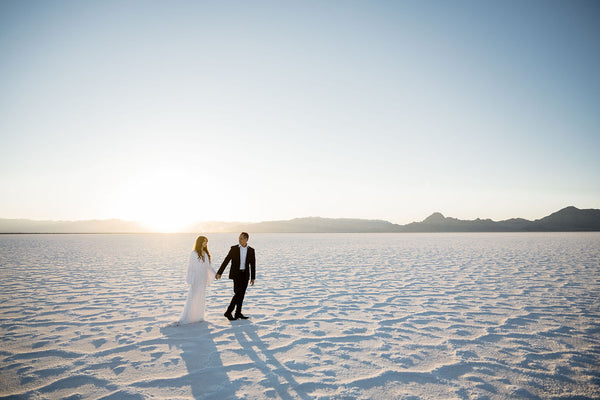 couple walking on the salt flats in a white dress and suit