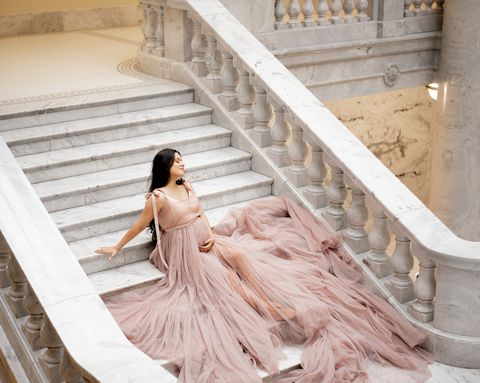 maternity photo in pink tulle dress, sitting on stairs