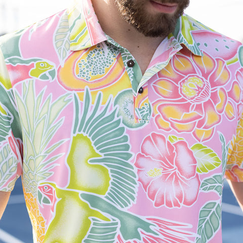 Close-up of a colorful golf polo shirt with a tropical pattern that includes large pink flowers, green leaves and colorful birds, adding a summery and playful style to golf attire.