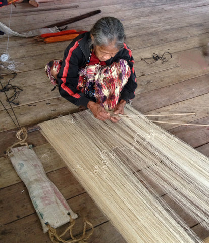 A photo of a woman of The T’boli Tribe in the Philippines weaving string to make fabric