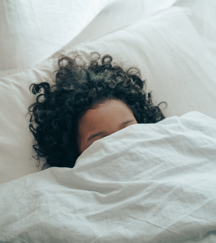 child buried under blanket