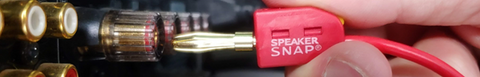 Red speaker snap connector being inserted into an amplifier, by hand