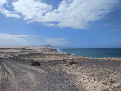Scenic view towards La Pared from dark rock formations, showcasing rugged coastal landscape and expansive vistas on Fuerteventura's West Coast.