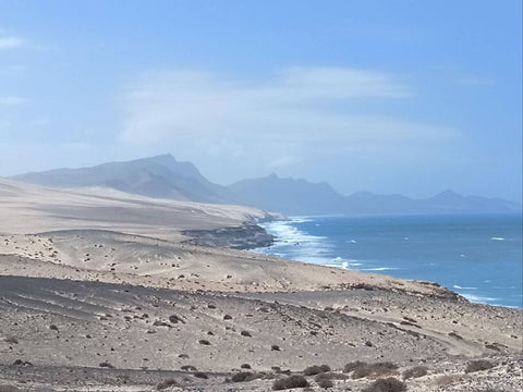 Panoramic view of Jandia Mountains in the distance, highlighting the rugged terrain and natural beauty of Fuerteventura's interior from the coastline.