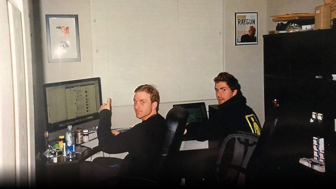 Two men are sitting in front of a computer.