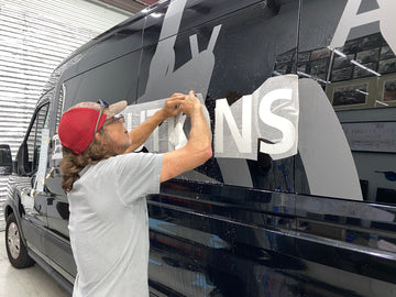 man putting a vinyl wrap on a vehicle