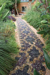 Anne's pebble mosaic footpath winds organically through a lush garden.