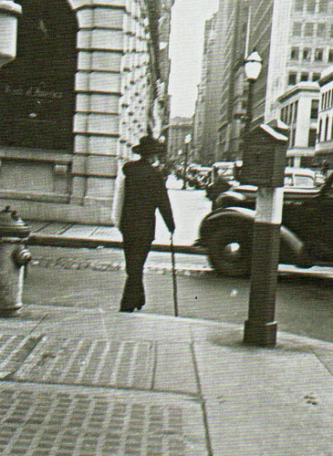 Maynard Dixon on San Francisco Street, circa 1930, carrying a painting and clutching his swordcane.