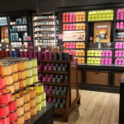 Dark, generic big box store with rows of colorful candles on black shelves. 