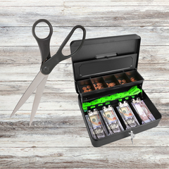 Black handled scissors and a black metal money box with cash inside and open lid on a grey wood background. 