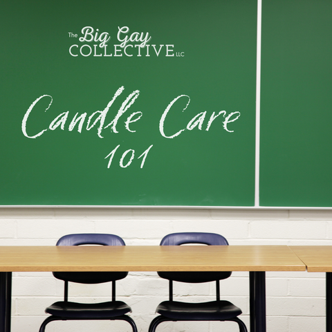 Green chalkboard with "The Big Gay Collective LLC" and "Candle Care 101" written on it with white chalk. Black classroom chairs behind a brown wood desk sit in front of the chalkboard, facing front.