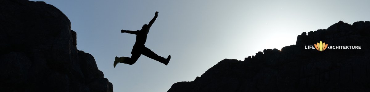 a man jumping between to rock over a cliff