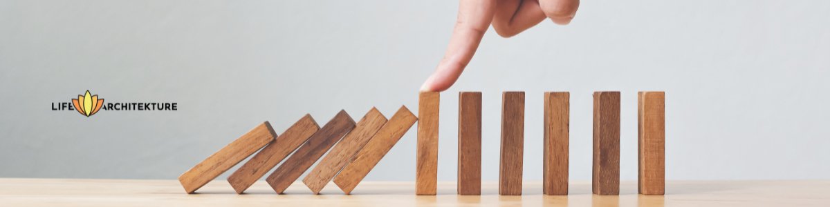 wooden dominos falling but stopped with a finger holding the next one