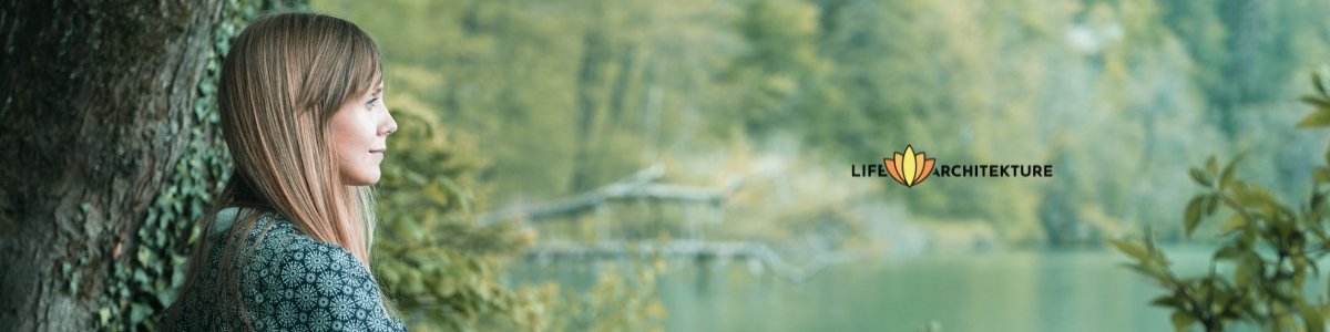 woman in the present moment seated by a lake looking far away