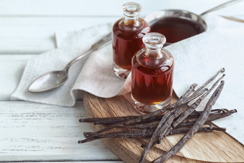 Bottles with aromatic extract and dry vanilla beans on board