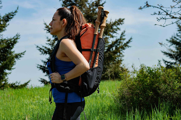 Hikers stands with trekking poles collapsed in pack pocket